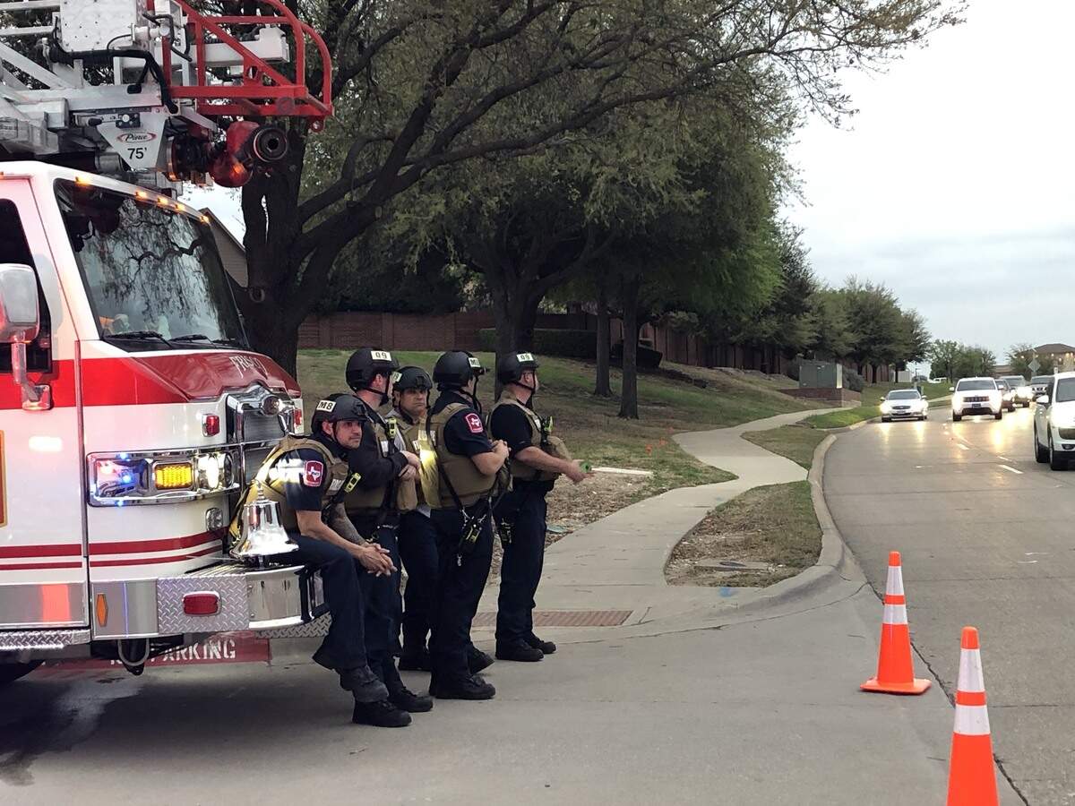 Police and firefighters monitor the area where a Texas state trooper was shot Friday, March 29 in Frisco as the search for the shooter continued.