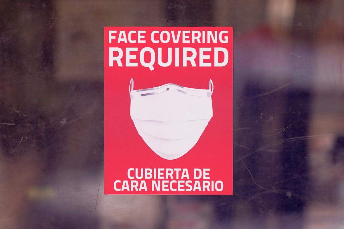 In this AP file photo from March 2, 2021, a mask required sign is displayed on the entrance to a business in Dallas. Hospitals across the state are feeling the crunch of the latest COVID-19 surge.