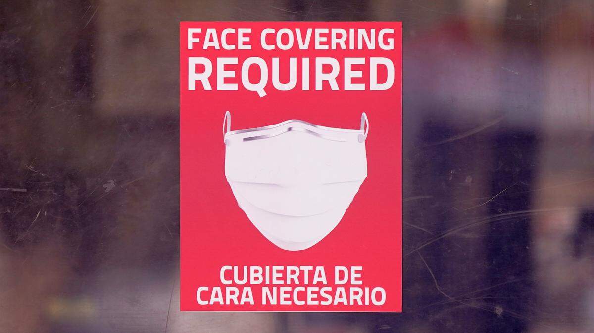 In this AP file photo from March 2, 2021, a mask required sign is displayed on the entrance to a business in Dallas. Hospitals across the state are feeling the crunch of the latest COVID-19 surge.