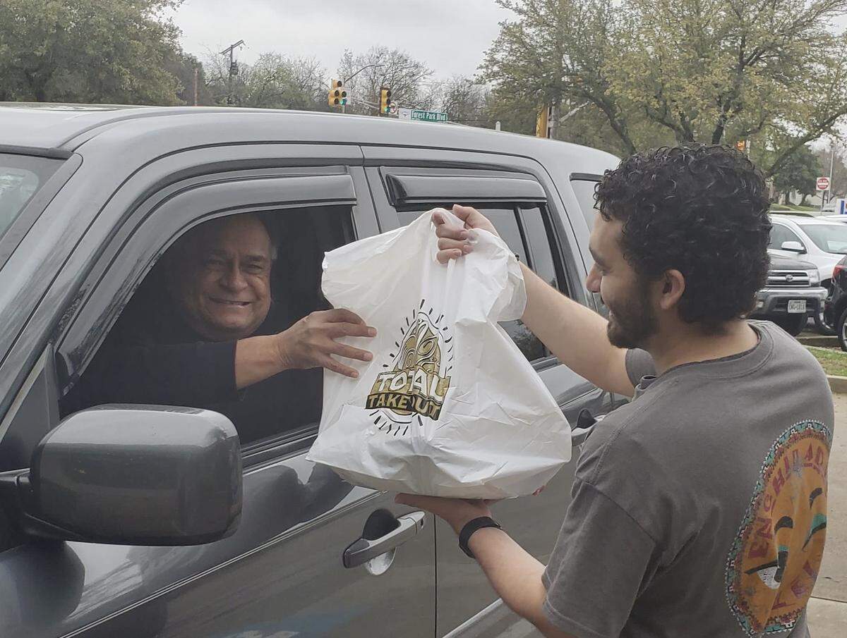 An Enchiladas Ole worker delivers an order for carryout.