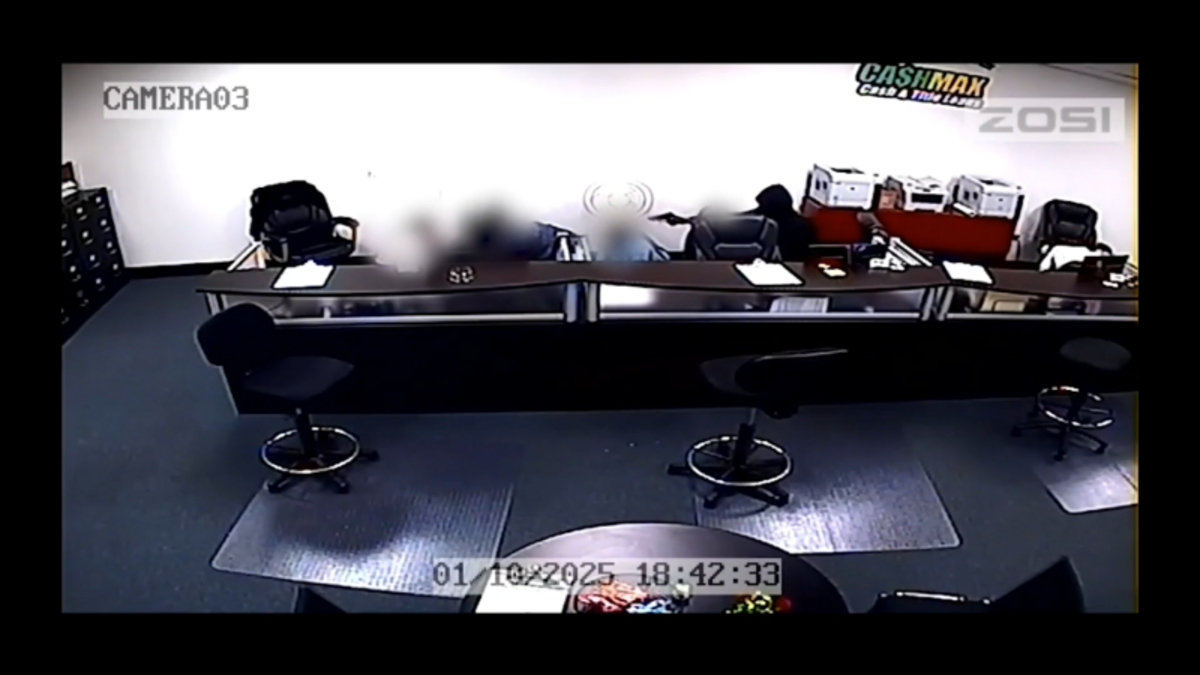 One of the suspects in the Jan. 10, 2025, robbery of a CashMax store in Arlington points a gun at employees in this image from video released by police. The robbers bound the employees’ arms and legs with tape, investigators said. Officers exchanged gunfire with one of the suspects, but no one was injured, according to police.