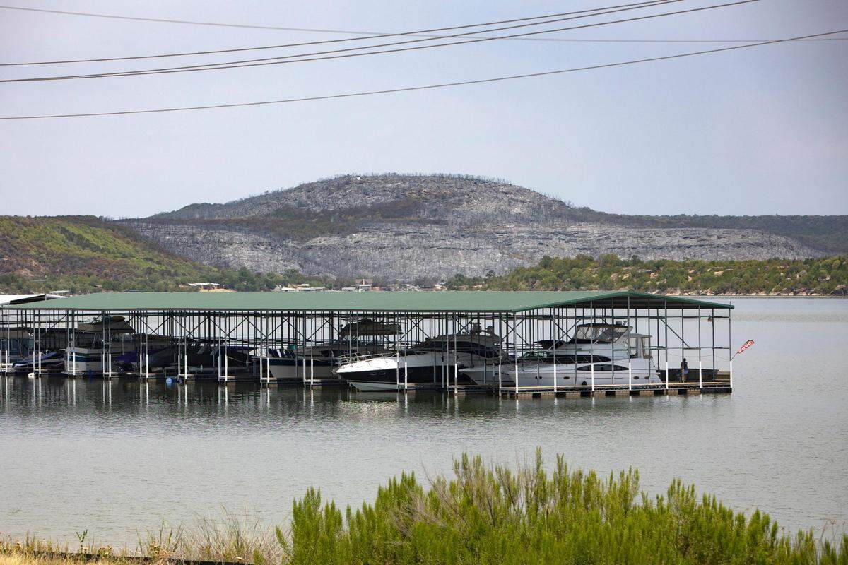Swathes of vegetation surround the area burnt by a wildfire that began Monday on Possum Kingdom Lake in Graford, Texas, on Wednesday, July 20, 2022.