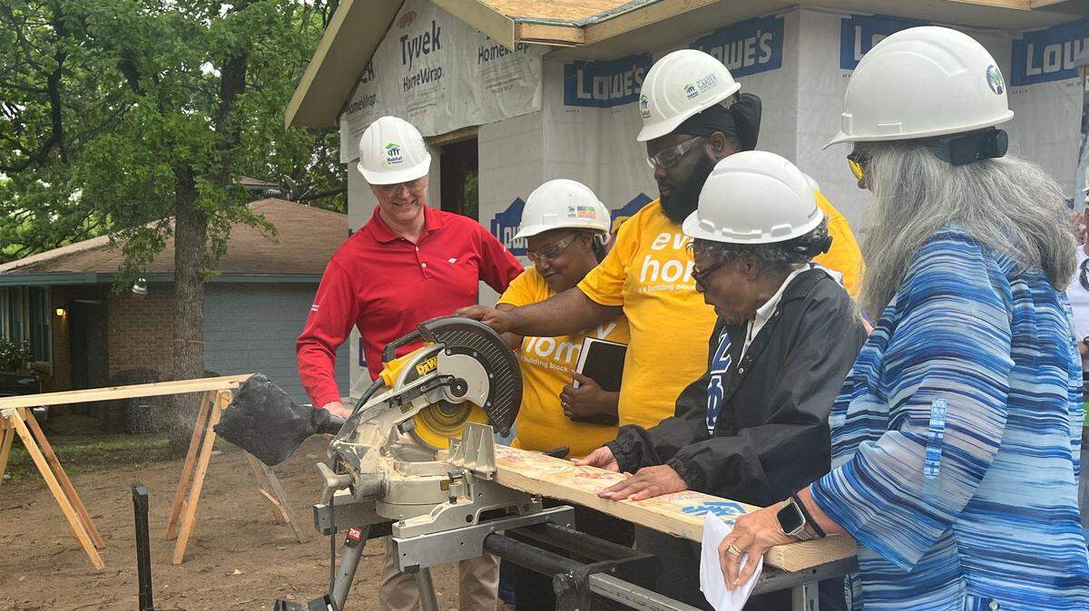 Shantequa and Paul Ingram, center in the yellow shirts, and Opal Lee, to Paul Ingram’s left, participate in a ceremonial board cutting for their new home in the Historic Rosedale Park neighborhood. The home is being built by Trinity Habitat for Humanity as part of the Opal Lee 100 Legacy Home initiative.
