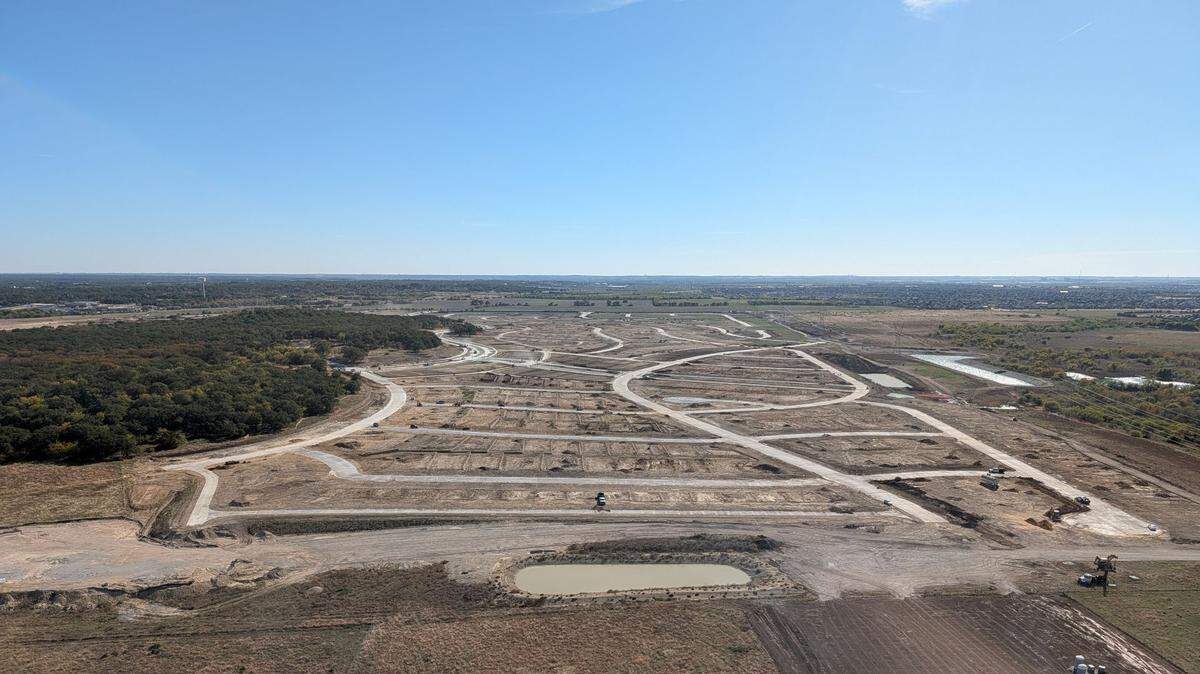An aerial shot of empty land cut up into streets and vacant lots taken from a helicopter on a blue sunny day.