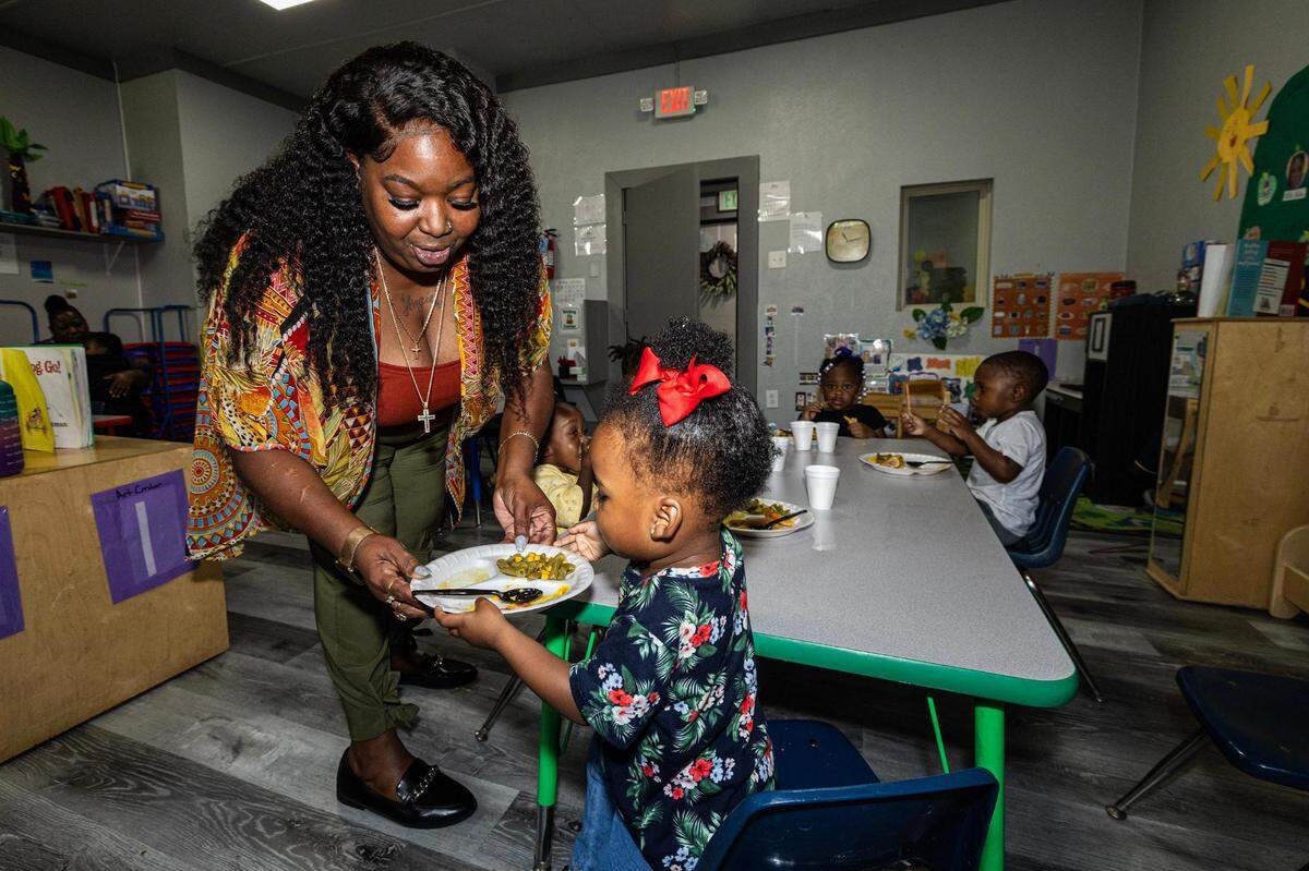 Angela James, the operator of Sunrise Early Learning and Development Center, helps Journi Qualls, 2, put away her plate during lunch break at the school in Fort Worth on Thursday, Oct. 26, 2023.
