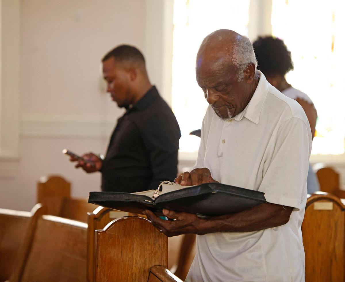 Ernest Mackey reads scripture from his bible along with pastor Lorenzo Jones during morning services at Mount Gilead Baptist Church in May. Mackey has been a member of the church for 48 years.