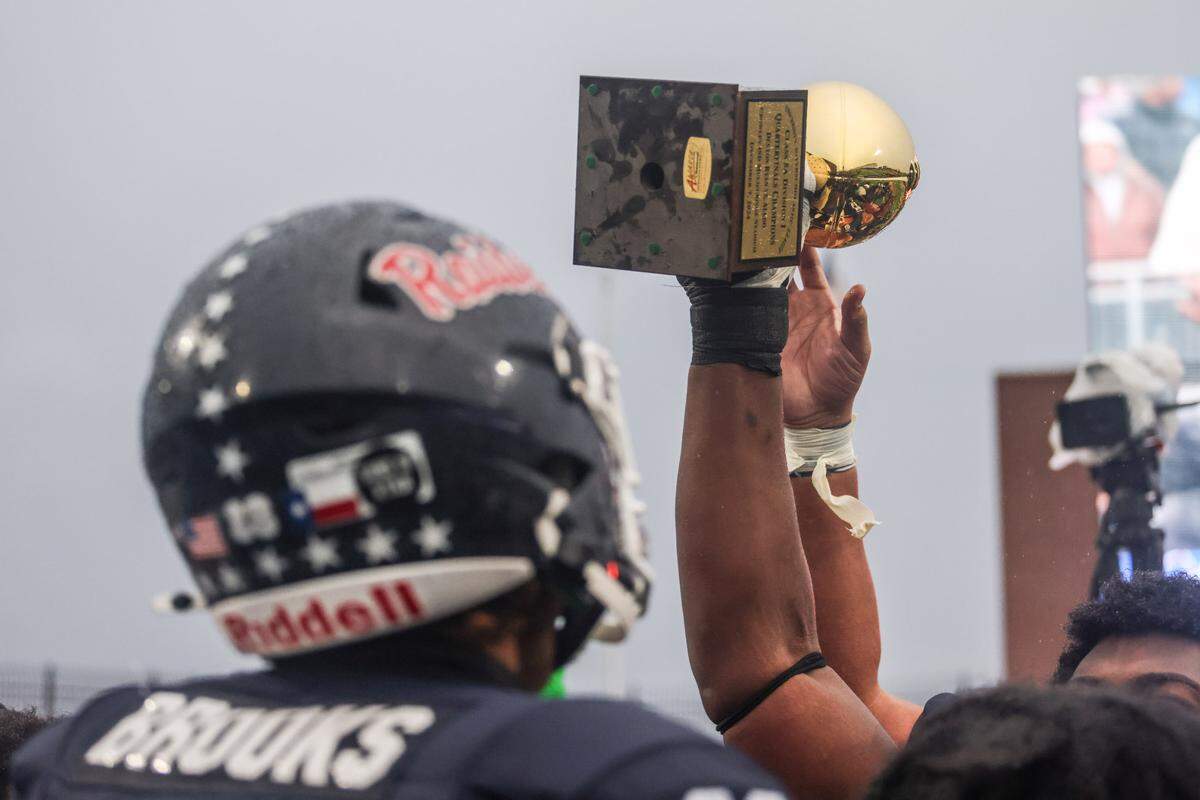 Denton Ryan players raise the trophy after defeating Aledo 31-21 in a Class 5A Division 1 state quarterfinal on Saturday, Dec. 7, 2024 at Crowley ISD Multi-Purpose Stadium in Fort Worth, Texas.