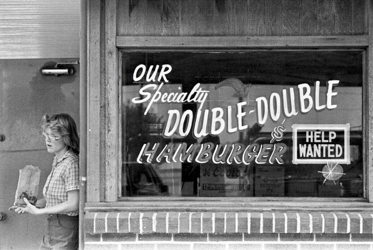 At Al’s Drive-In restaurant in Arlington, Missy Freede is seen in 1983 delivering a bag of burgers alongside an advertisement painted in the store’s window for the restaurant’s specialty of the Double-Double Hamburger next to a “Help Wanted” sign taped to the window.