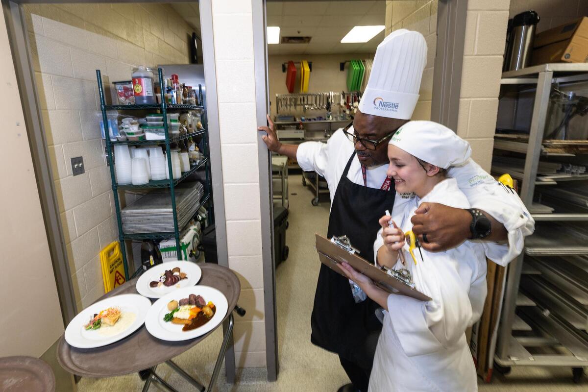 Chef David Roberson congratulates his student Julie Hedges after the team finished the three-course menu during a practice session at the kitchen in Ben Barber Innovation Academy in Mansfield on Friday, April 18, 2025.