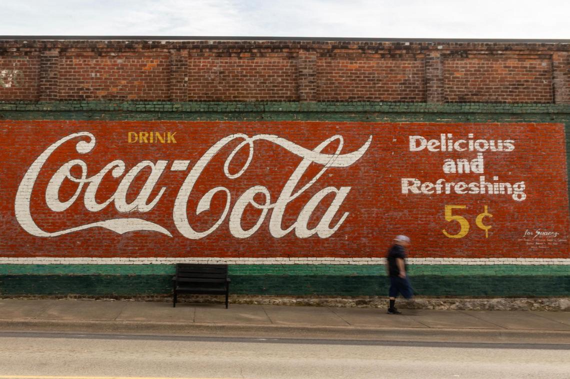 A man walks by the old Coca-Cola mural in Decatur’s courthouse square on Thursday, March 29, 2025.