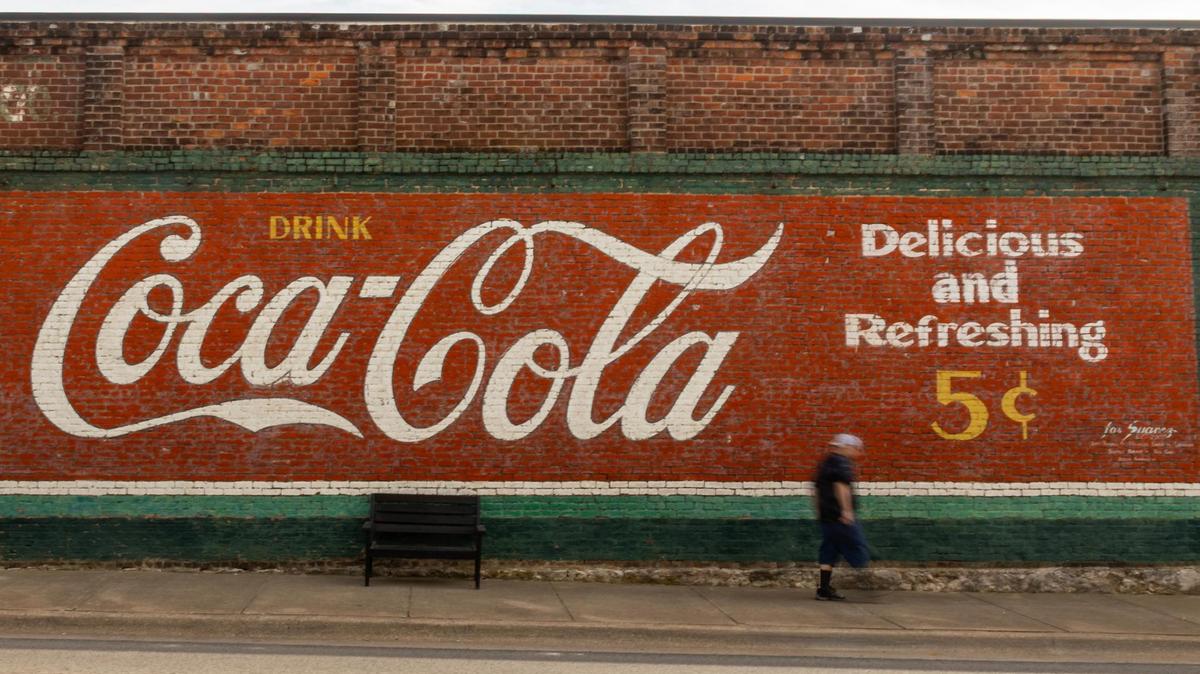 A man walks by the old Coca-Cola mural in Decatur’s courthouse square on Thursday, March 29, 2025.