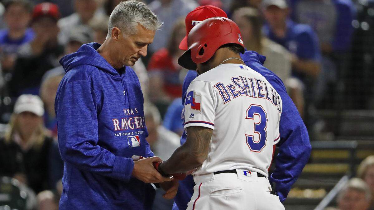 Trainers looked at the left hand of Rangers center fielder Delino DeShields in the seventh inning Friday night. DeShields was out of the lineup and having an MRI on Saturday afternoon.