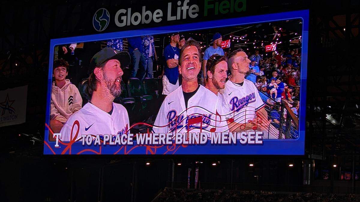 Four dudes singing a song in Rangers uniforms on the Jumbotron