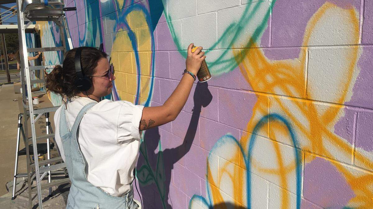 Artist Riley Morris spray paints the outline of a butterfly at Smart Parts Crafts in Hurst.