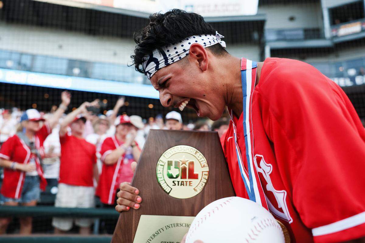 Grapevine catcher Gianni Corral celebrates while holding the championship trophy after the Mustangs defeated Kingwood Park 9-5 in the Class 5A Division II state championship game on June 6 at Dell Diamond in Round Rock.