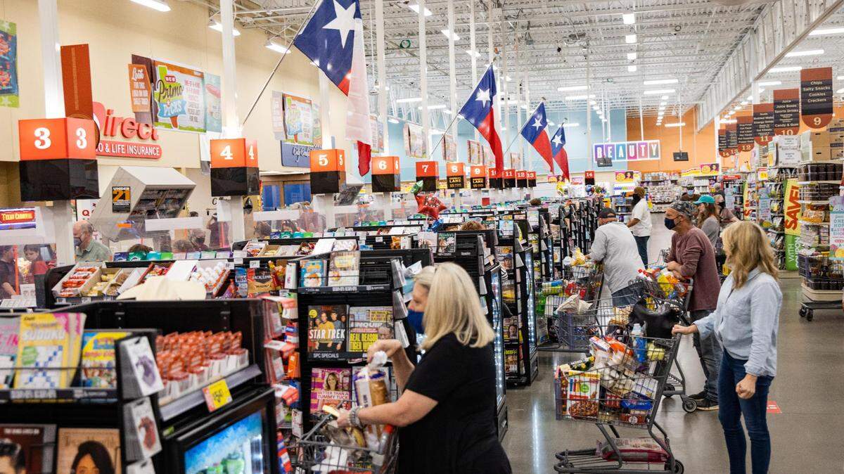 Texas flags are posted over the cash registers as customers wait to check out at the H-E-B in Hudson Oaks on Friday, March 26, 2021. 