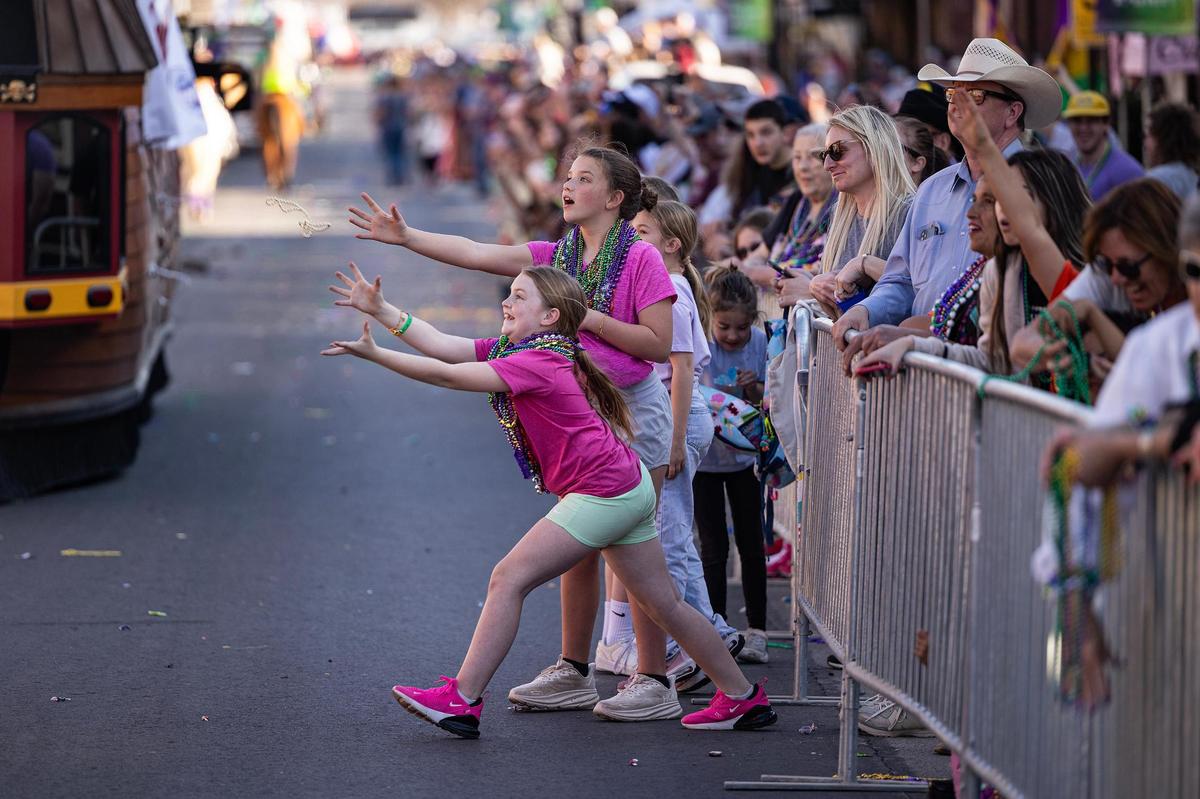 Parade spectators attempt to catch bead necklaces from the parade floats during the big parade for the 15th Annual Mardi Gras Nocona Style on Clay Street in Nocona on Saturday, Mar. 1, 2025.