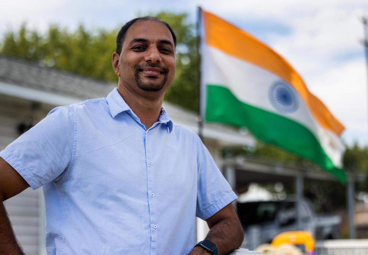 Dinesh Hooda, Sr. Technical Program Manager at Uber, stands near the National Flag of India at his home in McKinney.