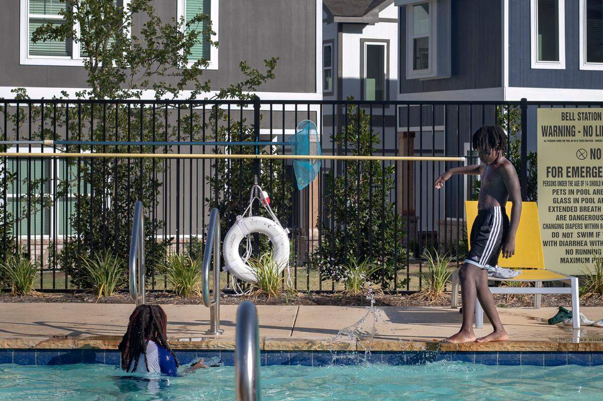 Khyli and Khyri Burnett cool off in the pool outside of their apartment at the Cottages at Bell Station in Hurst, Texas, on July 5, 2022.