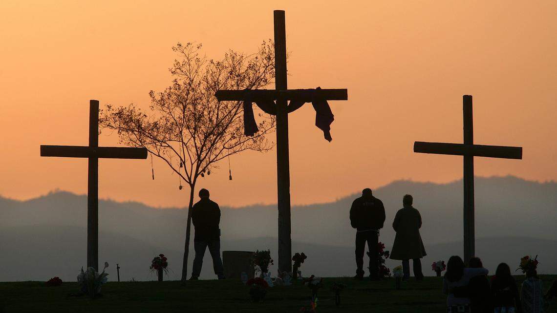 A group of people watch the sunrise at the Cross at Hillcrest Memorial Park after an Easter sunrise service held by Canyon Hills Assembly of God Church in Bakersfield California on Sunday, March 23, 2008. 