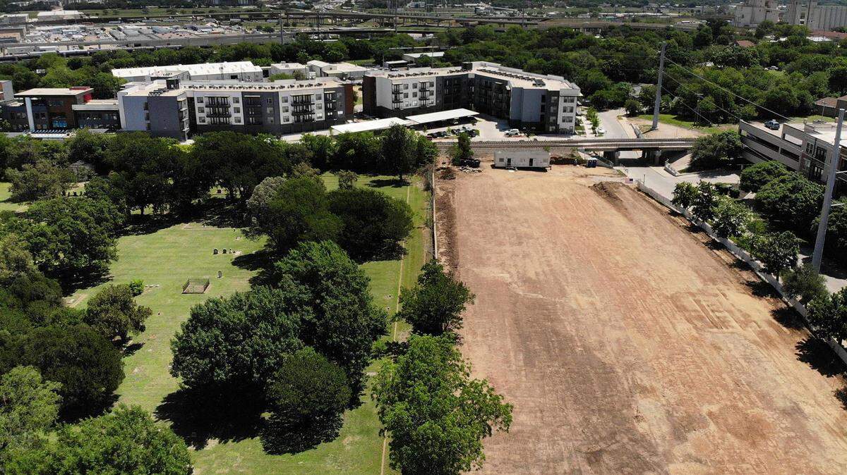 A small wall and fence separate land cleared for an upcoming 172-unit apartment from Pioneers Rest Cemetery, one of Fort Worth’s oldest cemeteries and a national landmark.