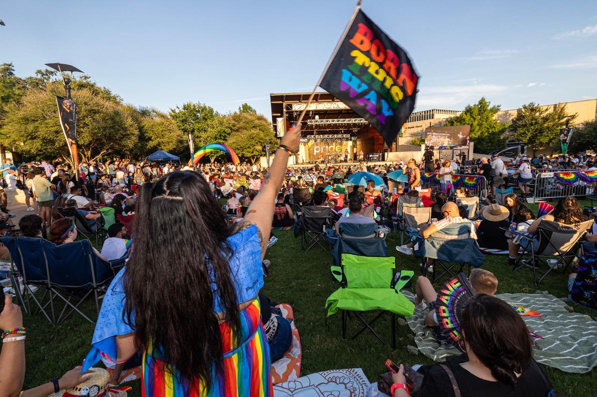 Cassandra Marquez waves a Pride flag saying “Born This Way” while dancing to a performance from Kameron Ross on stage at the Arlington Pride event at Levitt Pavilion in Arlington on Saturday, June 8, 2024.