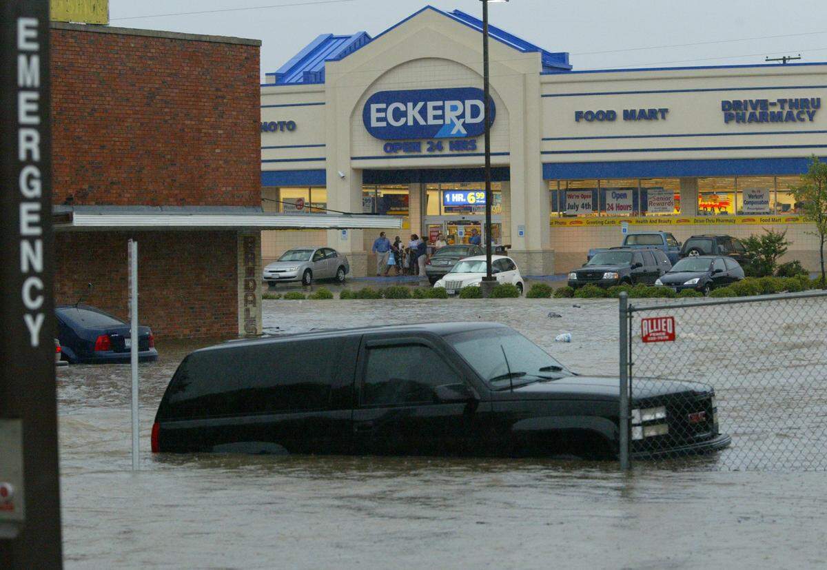 June 28, 2004: Cars in a flooded parking lot on the north side of Berry Street as Eckerd drugs clients watch from the porch. The water on Berry got as deep as 6 feet in the roadway. (The location today is a CVS.)