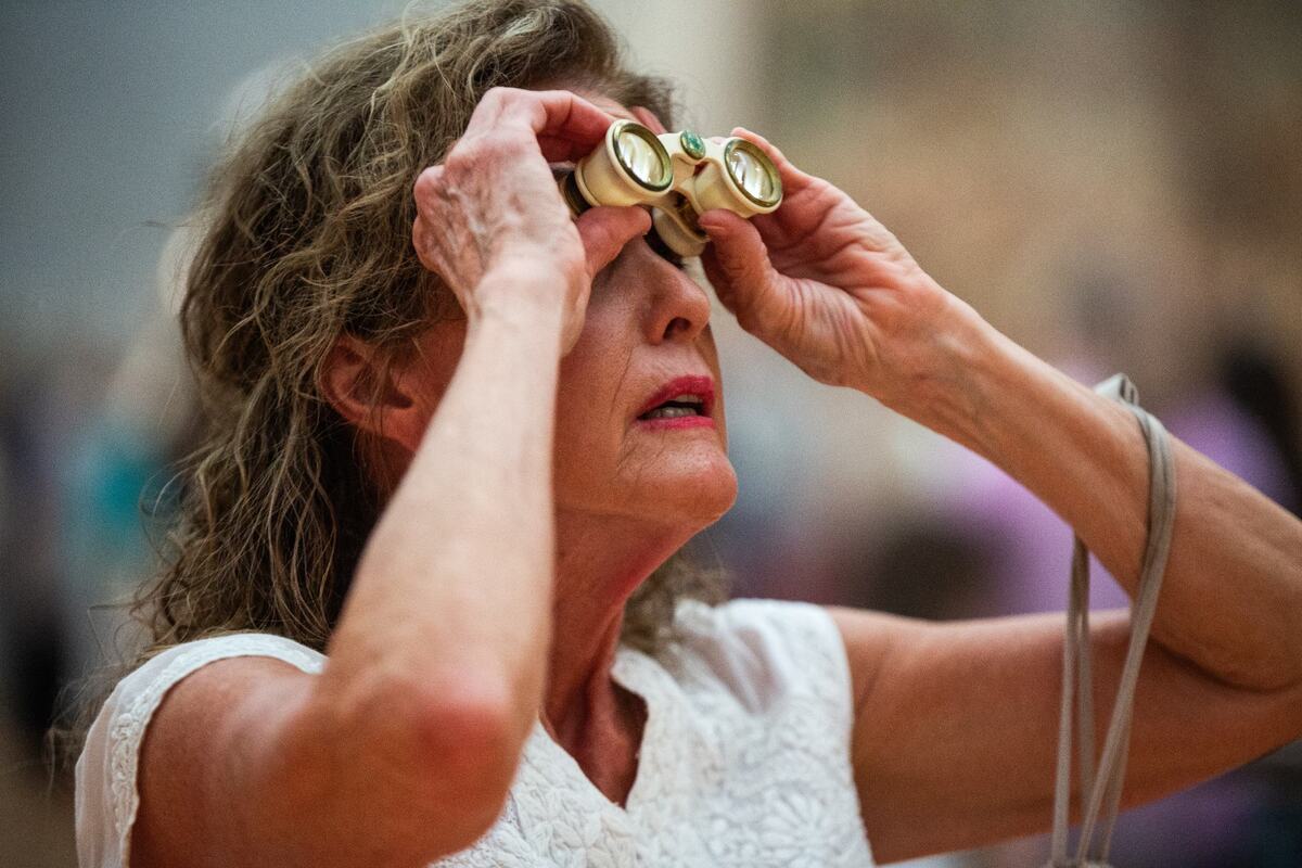 Docent Rebecca Pope looks through opera glasses at the ‘Art and War in the Renaissance: The Battle of Pavia Tapestries’ on Friday, June 14, 2024, at the Kimbell Art Museum. Bbinoculars or opera glasses allowed guests to better view the details on the tapestry due to its large size.