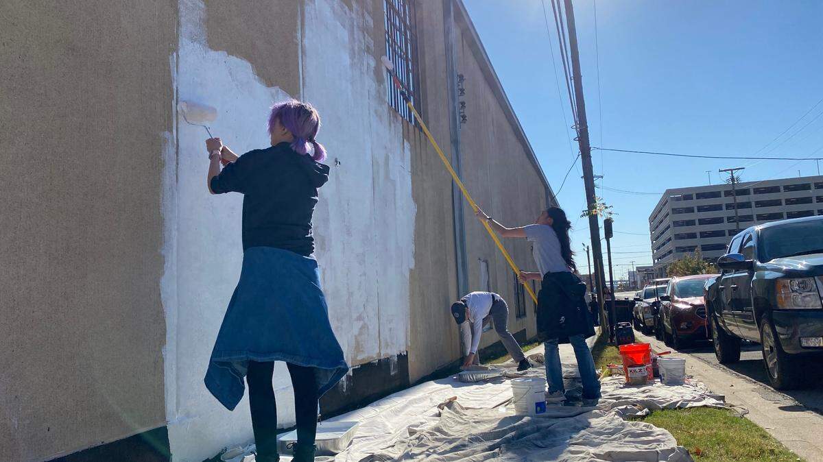 Anne Allen, her daughter and a friend began priming a downtown wall for a mural Saturday morning.