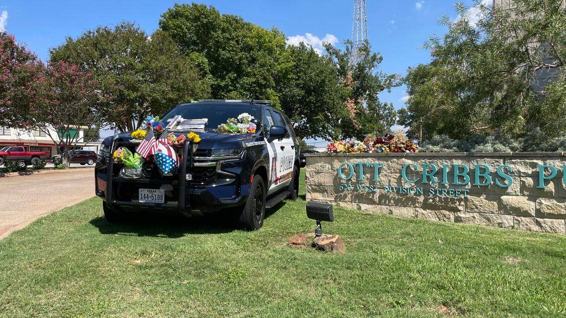 A memorial outside the Arlington Police Department headquarters pays tribute to Officer Darrin McMichael, who was killed in a hit and run. Investigators are still searching for the driver who hit him.