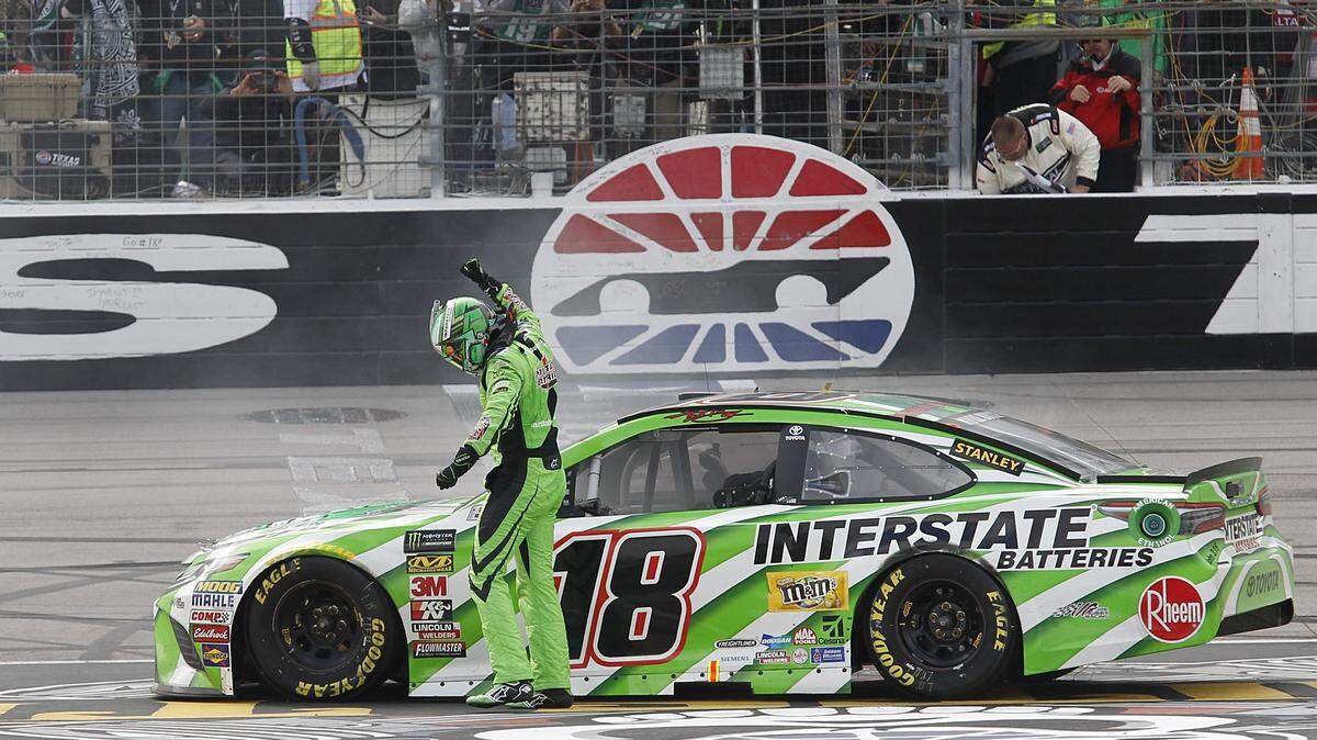 Kyle Busch (18) pumps his fist in victory as he goes to retrieve the checkered flag after winning the O'Reilly Auto Parts 500 race at Texas Motor Speedway in Fort Worth, TX April 8, 2018.