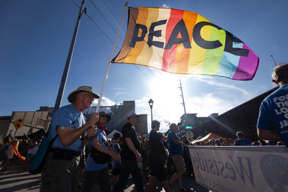 March participants walk with signs and flags down South Main Street during Trinity Pride Fest in Fort Worth on Saturday, June 28, 2025.