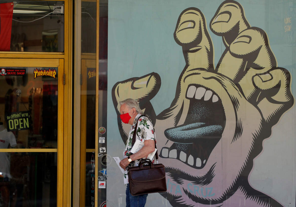 A man wearing a face mask for protection against COVID-19 passes a business that has reopened in San Antonio, Thursday, May 14, 2020. Texas attorney general Ken Paxton has warned officials in San Antonio, Austin and Dallas that the cities could face lawsuits if they do not relax coronavirus measures he says go further than state law allows. (AP Photo/Eric Gay)
