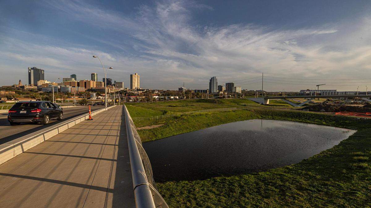 A bridge over a river with a city skyline in the distance. 