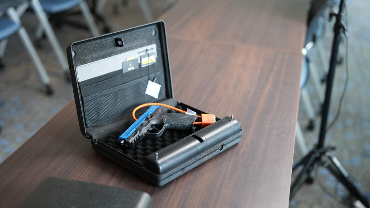 A gun lockbox is pictured with a gun that’s been disabled with a cable lock.