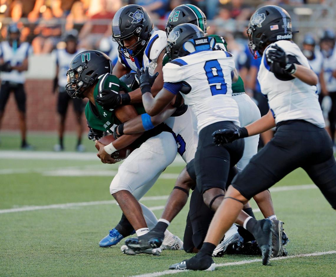 Lake Ridge quarterback Kennen Miller is brought down in the backfield by Summit defensive lineman Legend Journey (5) in the first half of a high school football game at Vernon Newsom Stadium in Mansfield, Texas, Friday, Aug. 26, 2022. Lake Ridge led Summit 42-14 at the half. (Special to the Star-Telegram Bob Booth)