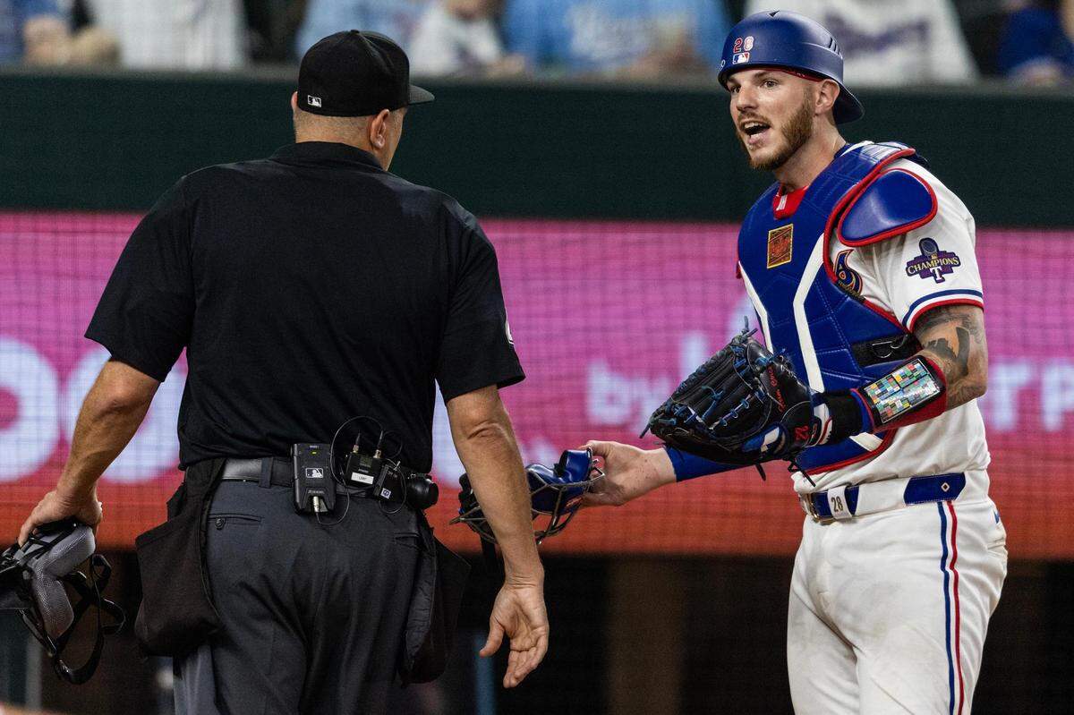 Home plate umpire Chad Fairchild argues with Texas Rangers catcher Jonah Heim after a controversial play allowed the Chicago Cubs to take the lead 3-2 in the top of the ninth inning in their season opener at Globe Life Field in Arlington on Thursday, March 28, 2024. Fairchild ruled that the Cub’s Mastrobuoni swung and missed when it was foul tipped and got past Heim. This allowed Cub’s Michael Busch to take advantage and advance to third base and eventually to home plate.