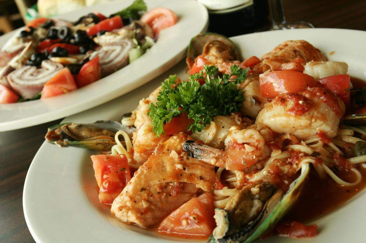 Zuppa di pesce (seafood combination sauteed in a zesty marinara sauce) and antipasto salad served at Moni’s.