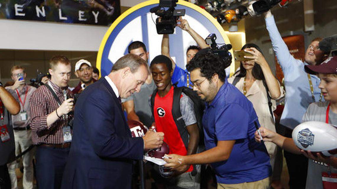 Texas A&M head coach Jimbo Fisher signs autographs for fans as he arrives for NCAA college football Southeastern Conference media days at the College Football Hall of Fame in Atlanta, Monday, July 16, 2018. (AP Photo/John Bazemore)