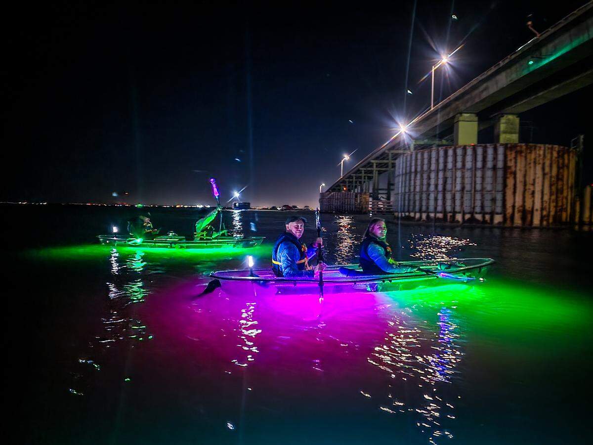 Paddlers glide under the John F. Kennedy Memorial Causeway on the calm waters of Laguna de Madre near North Padre Island. The Glow Row are guided tours on the saltwater lagoon a few minutes from downtown Corpus Christi.