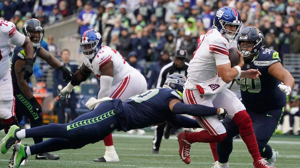New York Giants quarterback Daniel Jones, second from right, runs against Seattle Seahawks linebacker Uchenna Nwosu, left, and defensive tackle Bryan Mone (90) during the second half on Sunday.