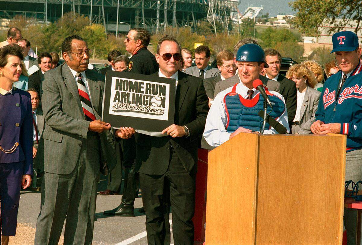 On Nov. 20, 1990, Arlington Councilman Elzie Odom stands with Mayor Richard Greene at an event to launch a campaign to finance a new stadium for the Texas Rangers baseball team. Nolan Ryan is to the far right; former President George W. Bush, a team owner, stands in the background.