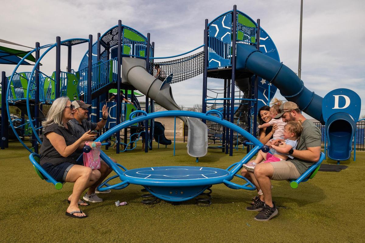 Sunset residents Holly and Colin Galdo, left, ride a seesaw with their daughter Leann Brown, son-in-law Max, and twin-granddaughters Ava and Emma, 2, in Harmon Park in Decatur on Thursday, March 29, 2025. The Browns said they welcome growth of Decatur, but hope the city implements more resources and amenities to accommodate all of its residents.