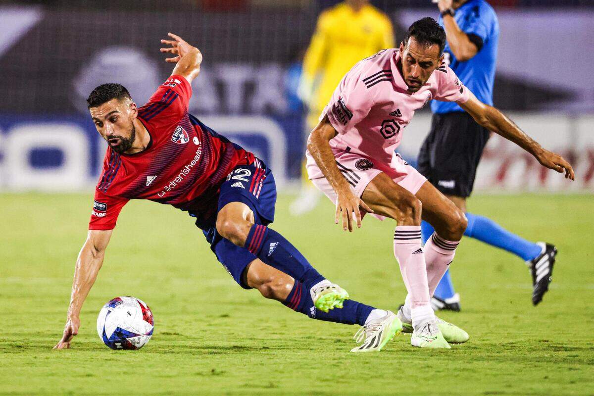 FC Dallas forward Sebastian Lletget (12) gets knocked down by Inter Miami CF defender Sergio Busquets (5) in the first half during a Leagues Cup match at TOYOTA Stadium in Frisco, Texas on Sunday, Aug. 6, 2023.