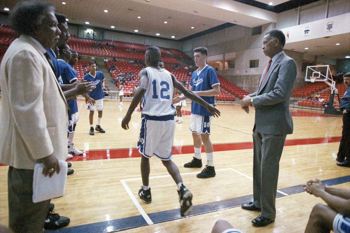 Dunbar High School basketball players are seen entering on to the court before a game against at the Wilkerson-Greines Activity Center in Fort Worth. Dunbar head coach Robert Hughes is seen at right with assistant coach Leondas Rambo at left.