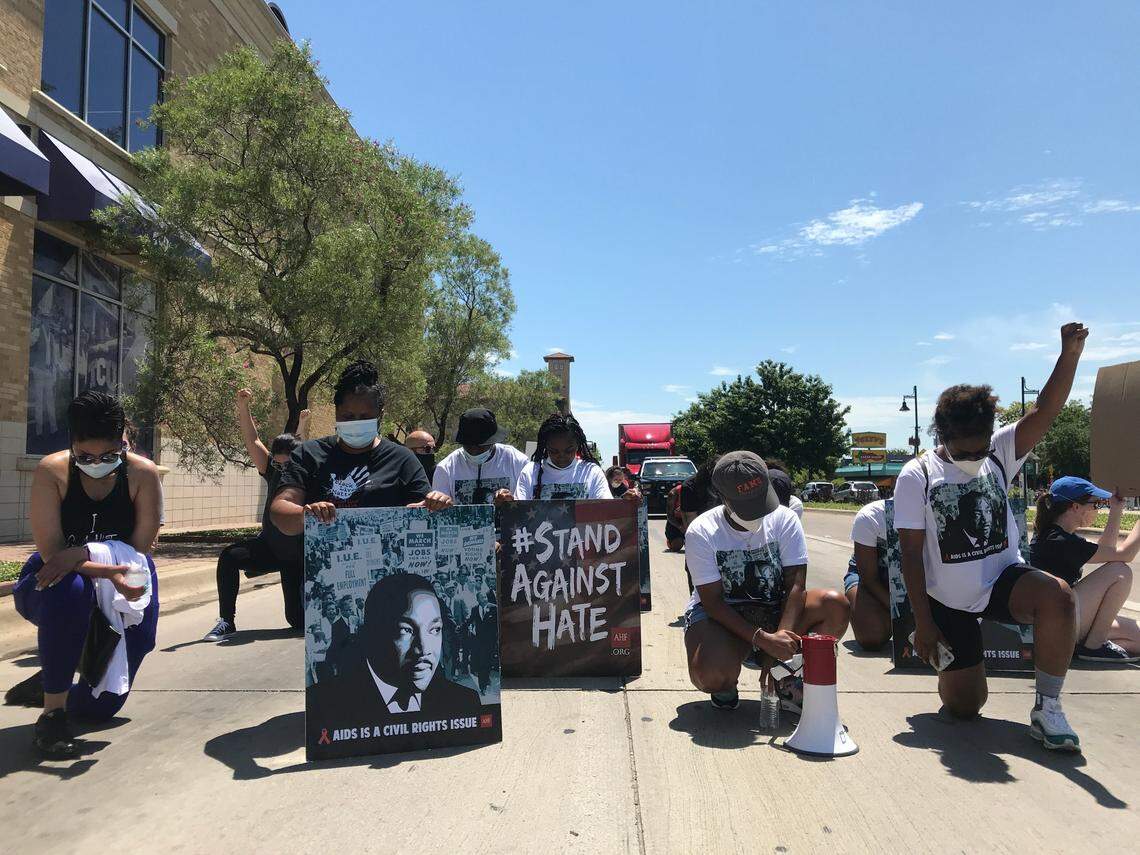 Protesters kneel in the middle of West Berry Street on Saturday afternoon to honor George Floyd. They were marching to TCU to call out incidents of alleged racism on campus and push for changes.