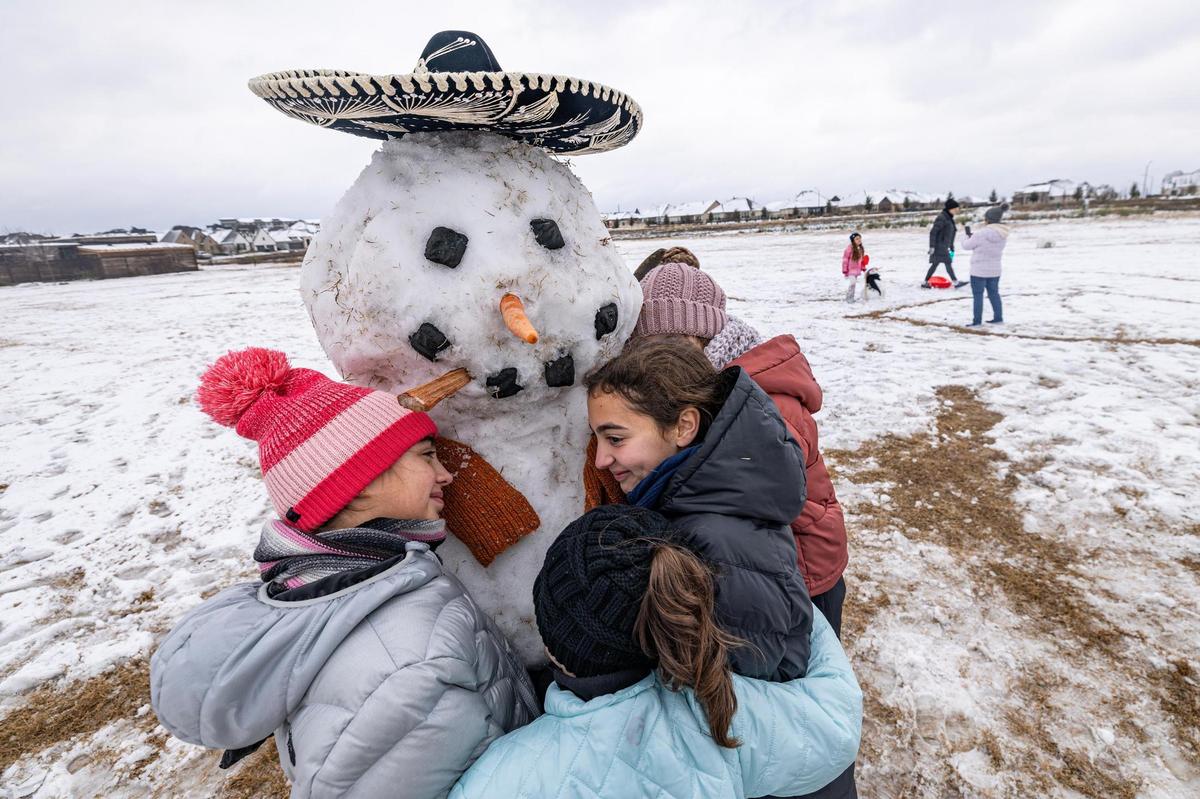 Neighborhood friends Annabelle, 10, Vivian Gonzalez, 12, and Erin Kate Ketterick, 13, hug their snowman named ‘Tiny Tim’ after building him at their neighborhood park in southwest Fort Worth on Friday, Jan. 10, 2025.