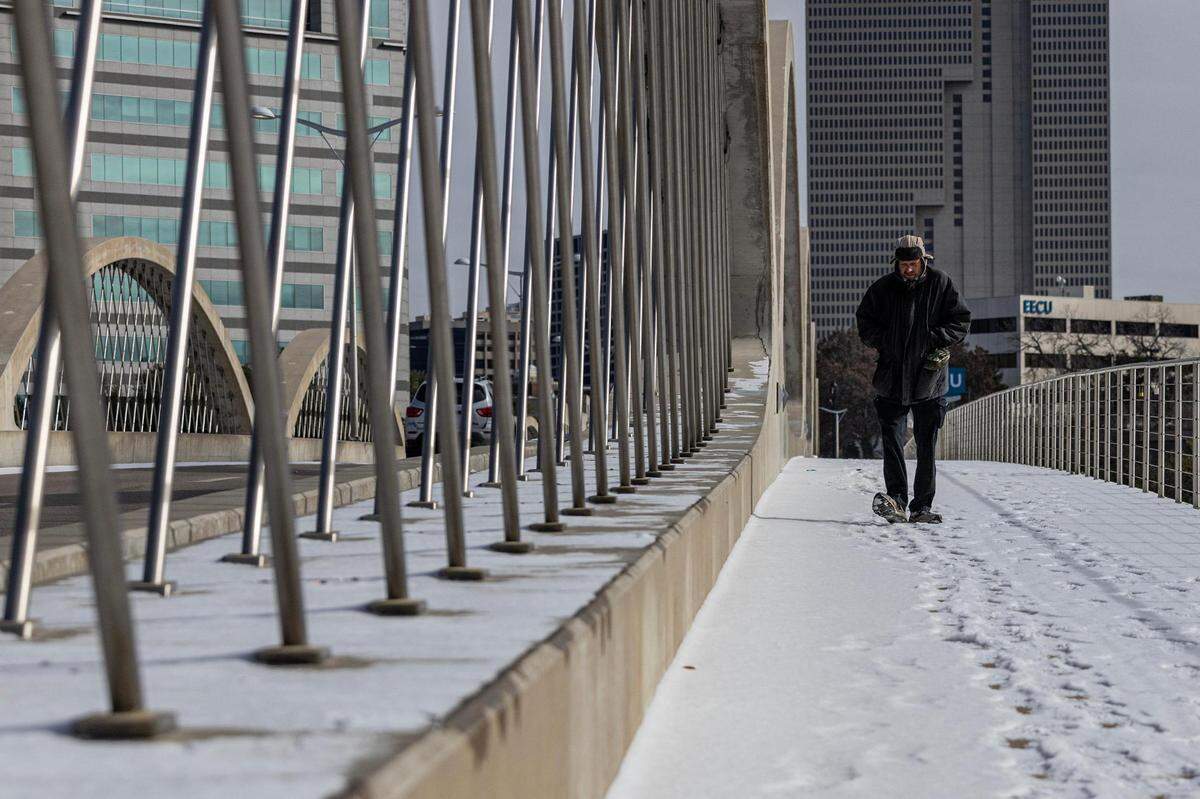 A man walks on the snowy Trinity River Bridge near downtown Fort Worth on Monday, Jan. 15, 2024.