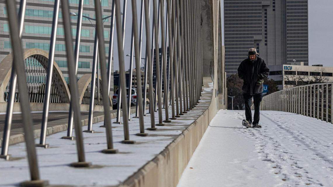 A man walks on the snowy Trinity River Bridge near downtown Fort Worth on Monday, Jan. 15, 2024.