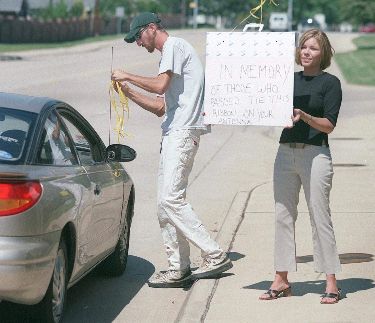 Windmill Terrace Apartment employees Mark Rigsby of Fort Worth and Apryl Beaty of Arlington tie yellow ribbons to antennas of passing motorists on Murphy Road in Bedford on Sept. 12, 2001.